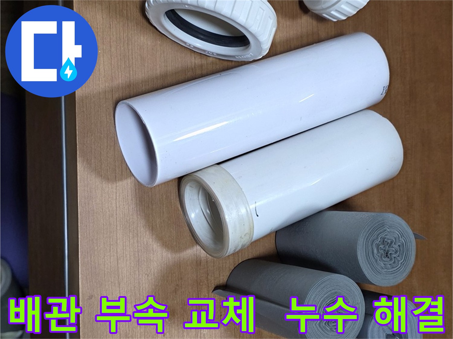 누수 해결을 위해 준비된 다양한 배관 부속 - T자관, 엘보, 소켓과 누수 방지 테이프가 놓여 있습니다.