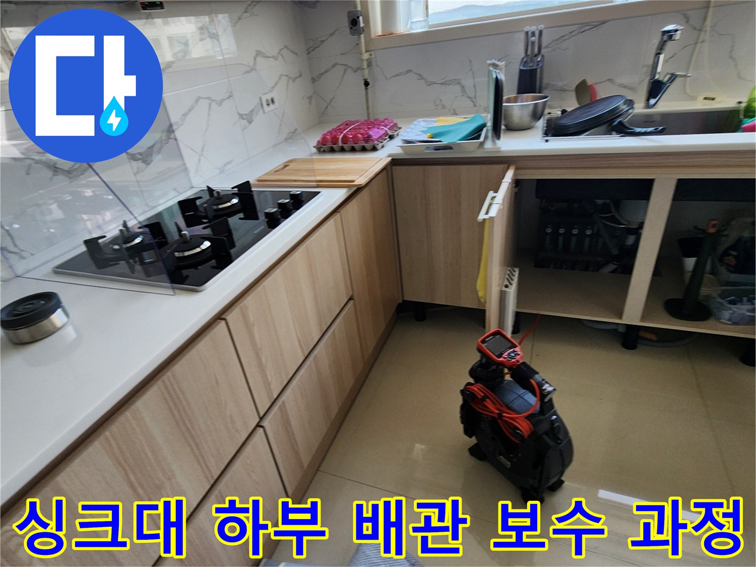 배관 수리를 위해 싱크대 아래쪽을 점검하고 정리한 모습