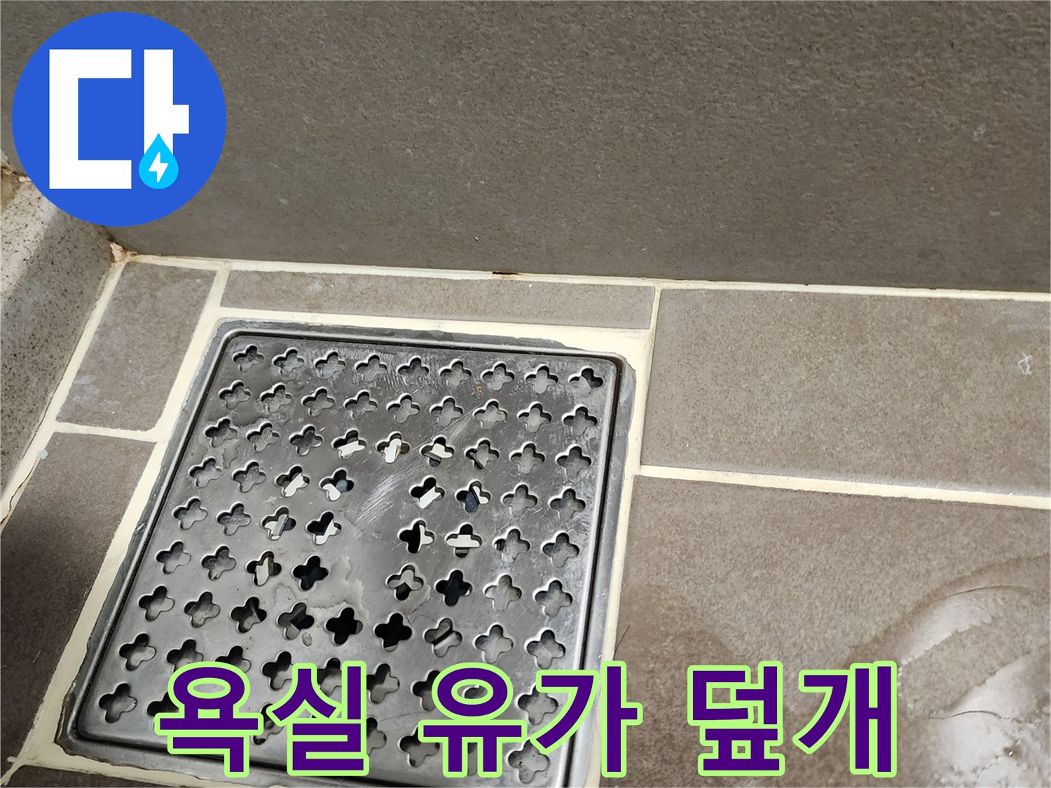 금속 재질의 욕실 배수구 덮개와 주변 타일 마감