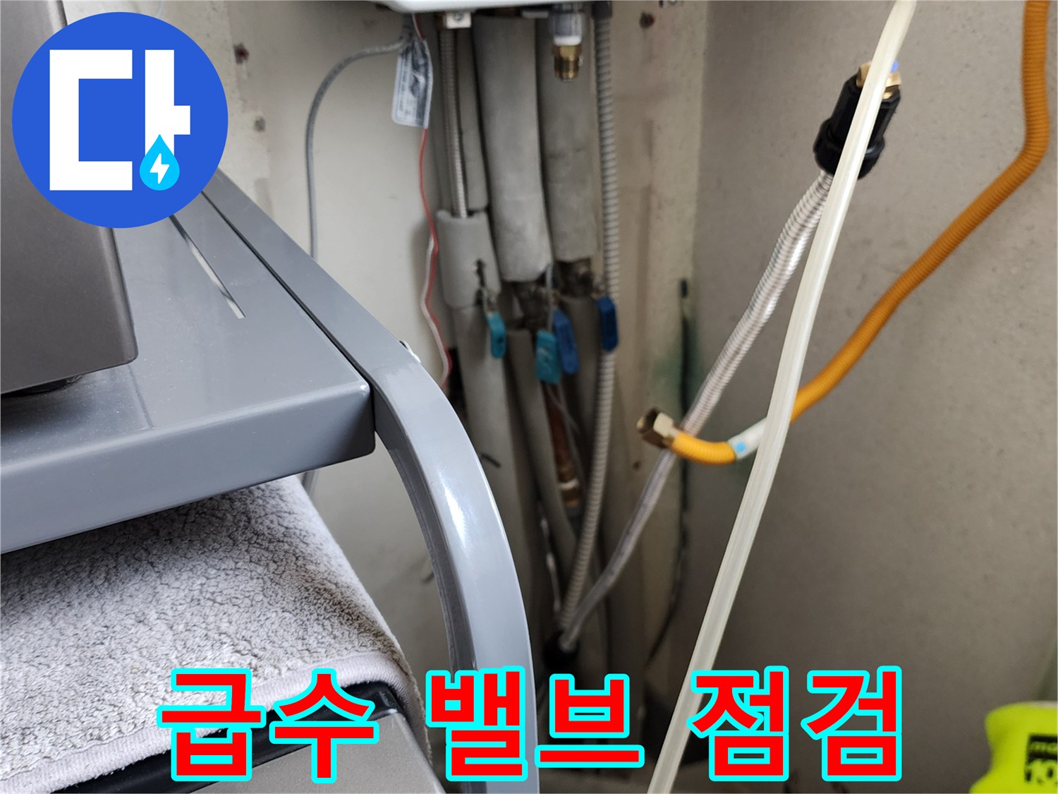 세탁실 벽면 밸브와 노란색 호스가 연결된 배관 부위 상세 사진