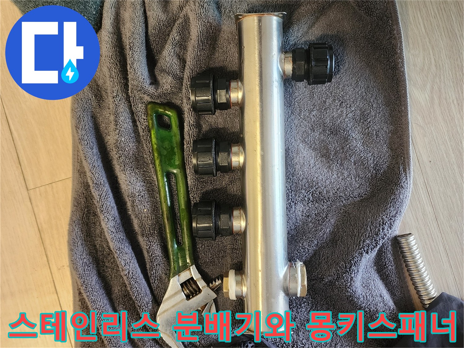 스테인리스 재질의 매립형 분배기와 작업용 몽키스패너가 수건 위에 놓여 있는 모습