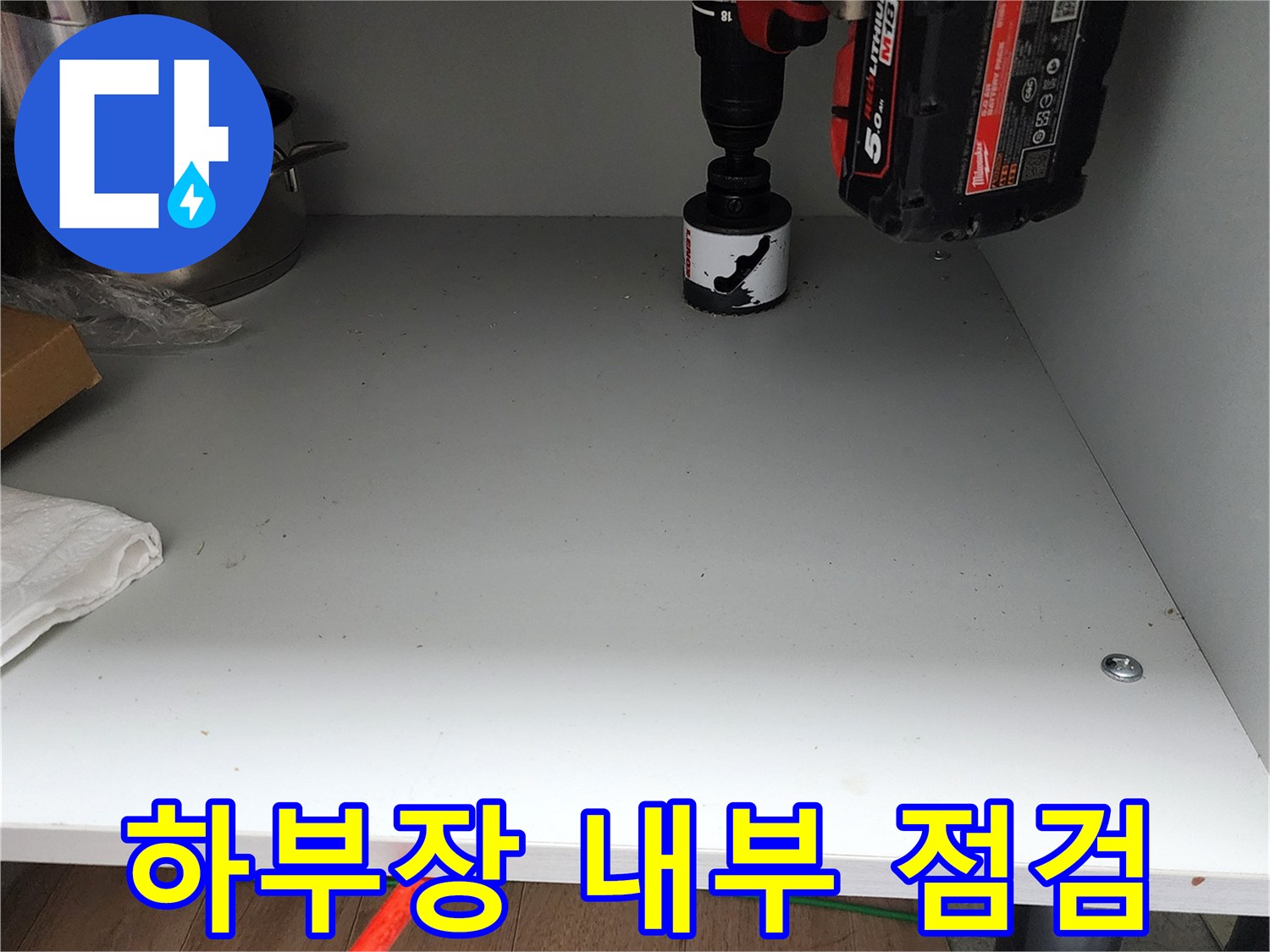 싱크대 하단 바닥에 놓인 전동 드릴과 작업용 도구들