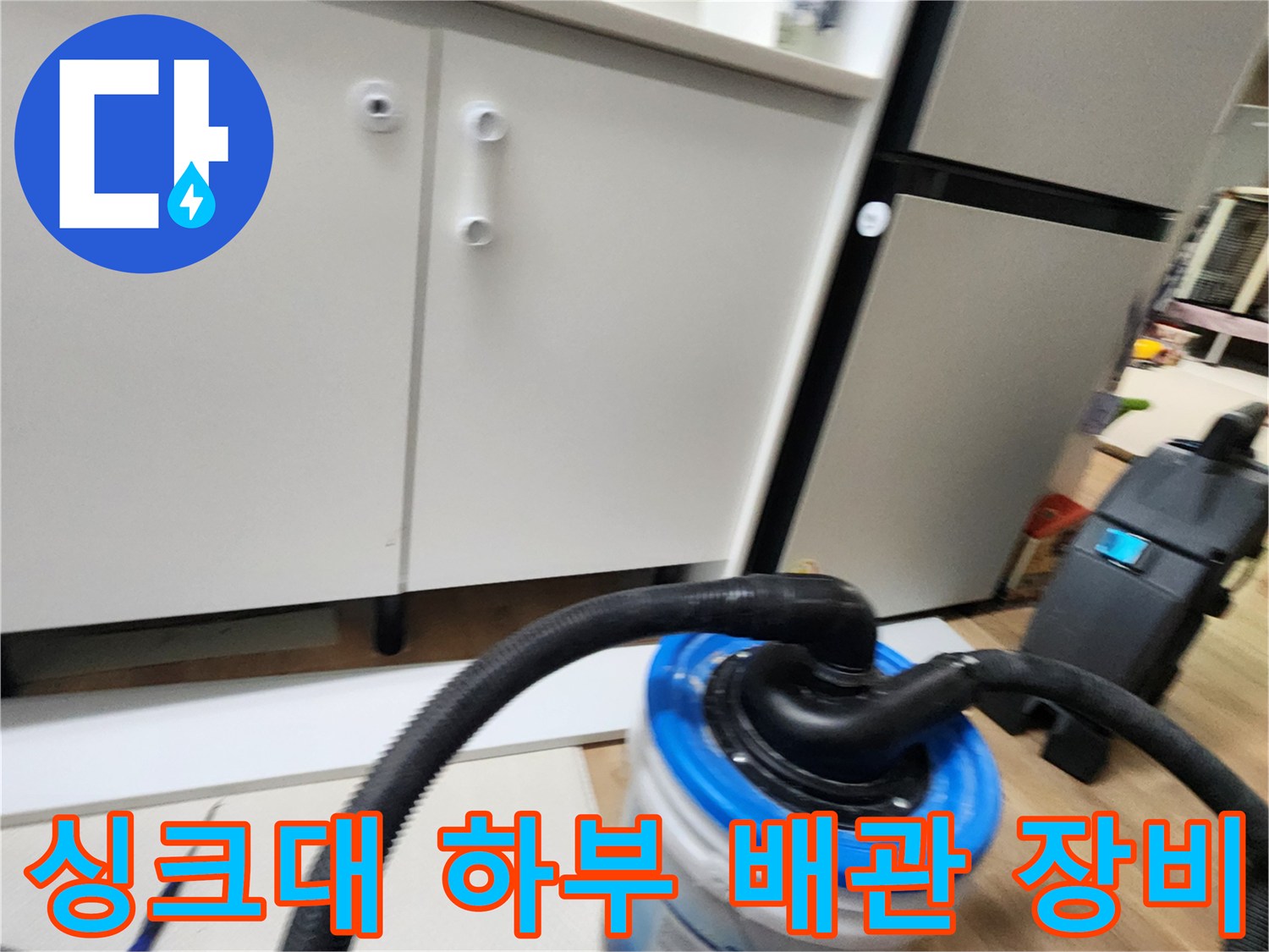주방 싱크대 아래쪽에서 배관 상태를 확인하기 위해 배치된 흡입 장비와 통