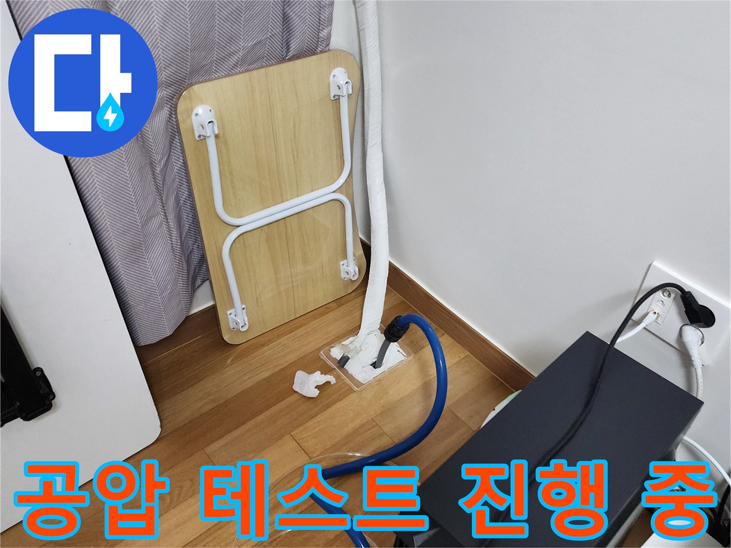 바닥 배관 연결부에-연결된 파란색 호스와 압력 장비 모습