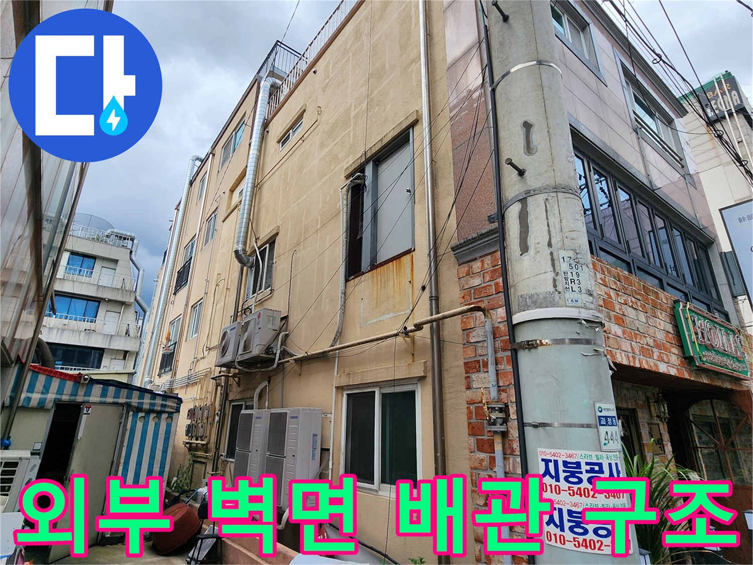 건물 외벽의 수직 배관과 에어컨 실외기 연결 부위 근접 촬영