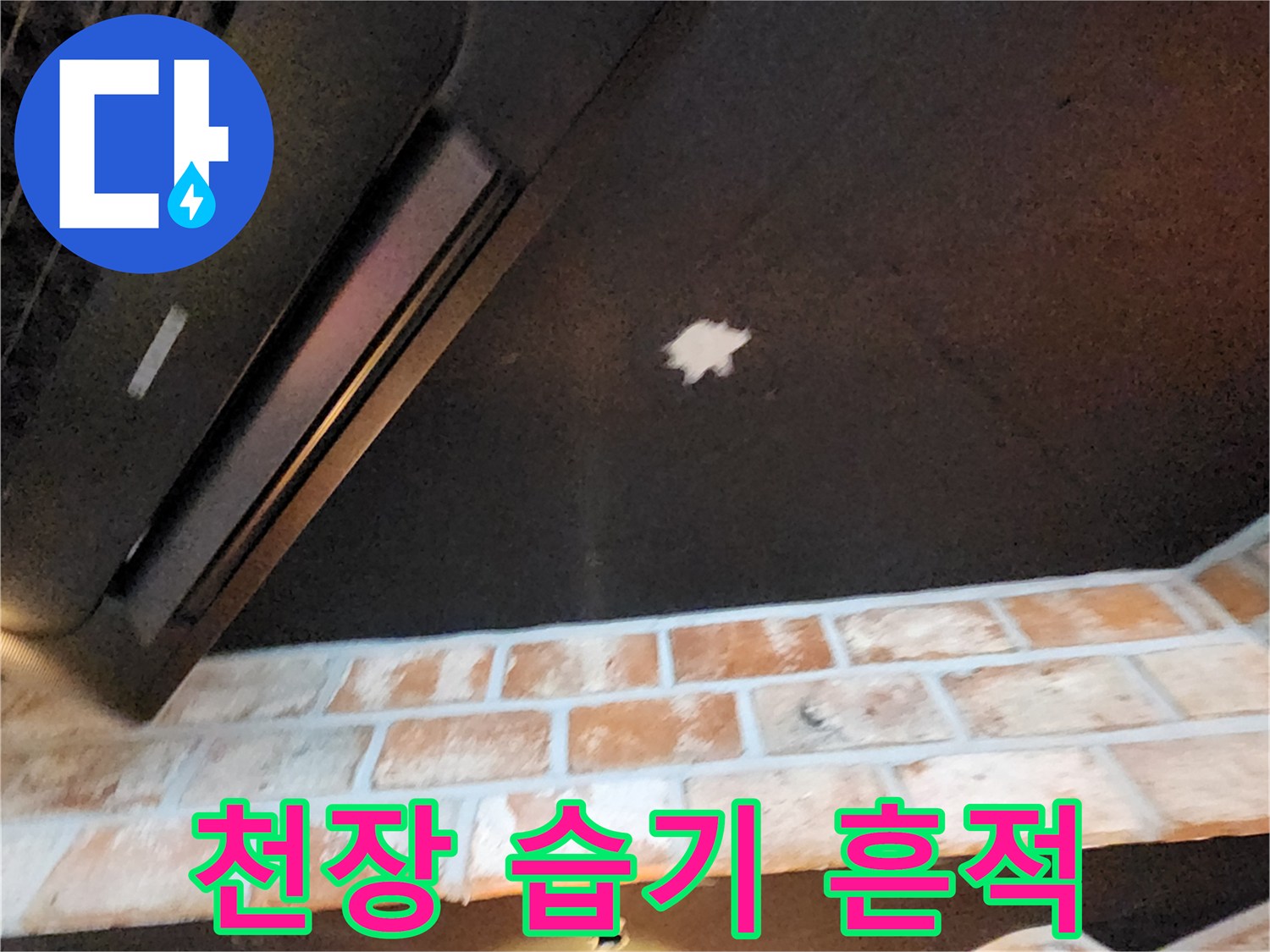 어두운 천장 중앙의 하얀 누수 자국과 벽돌 구조물