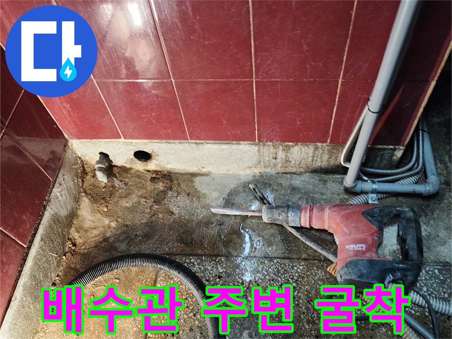 함마드릴을 사용하여 싱크대 하부 배관 부근의 시멘트를 제거하는 장면