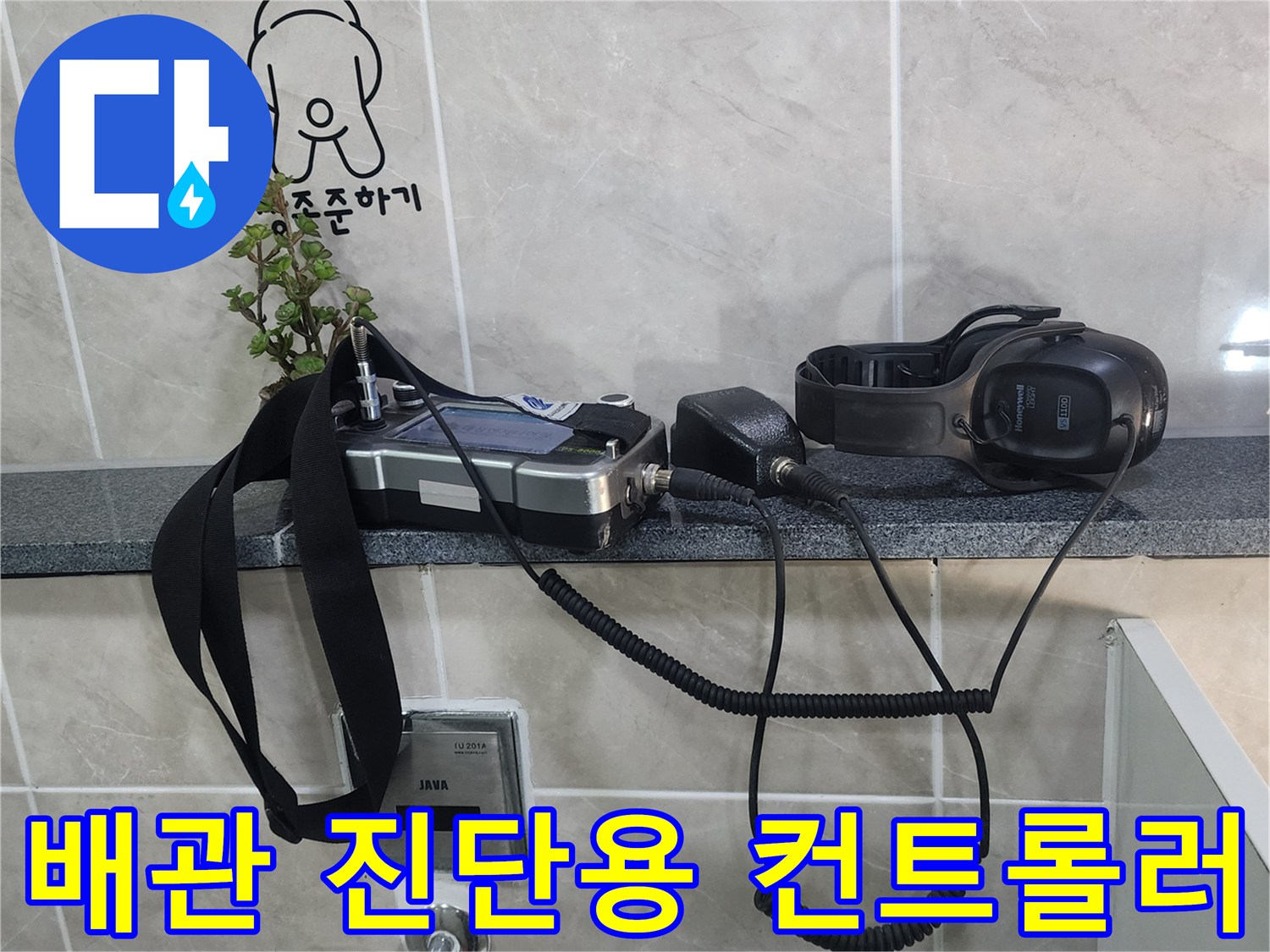 타일 선반에 놓인 배관 탐지기 본체와 헤드 장비