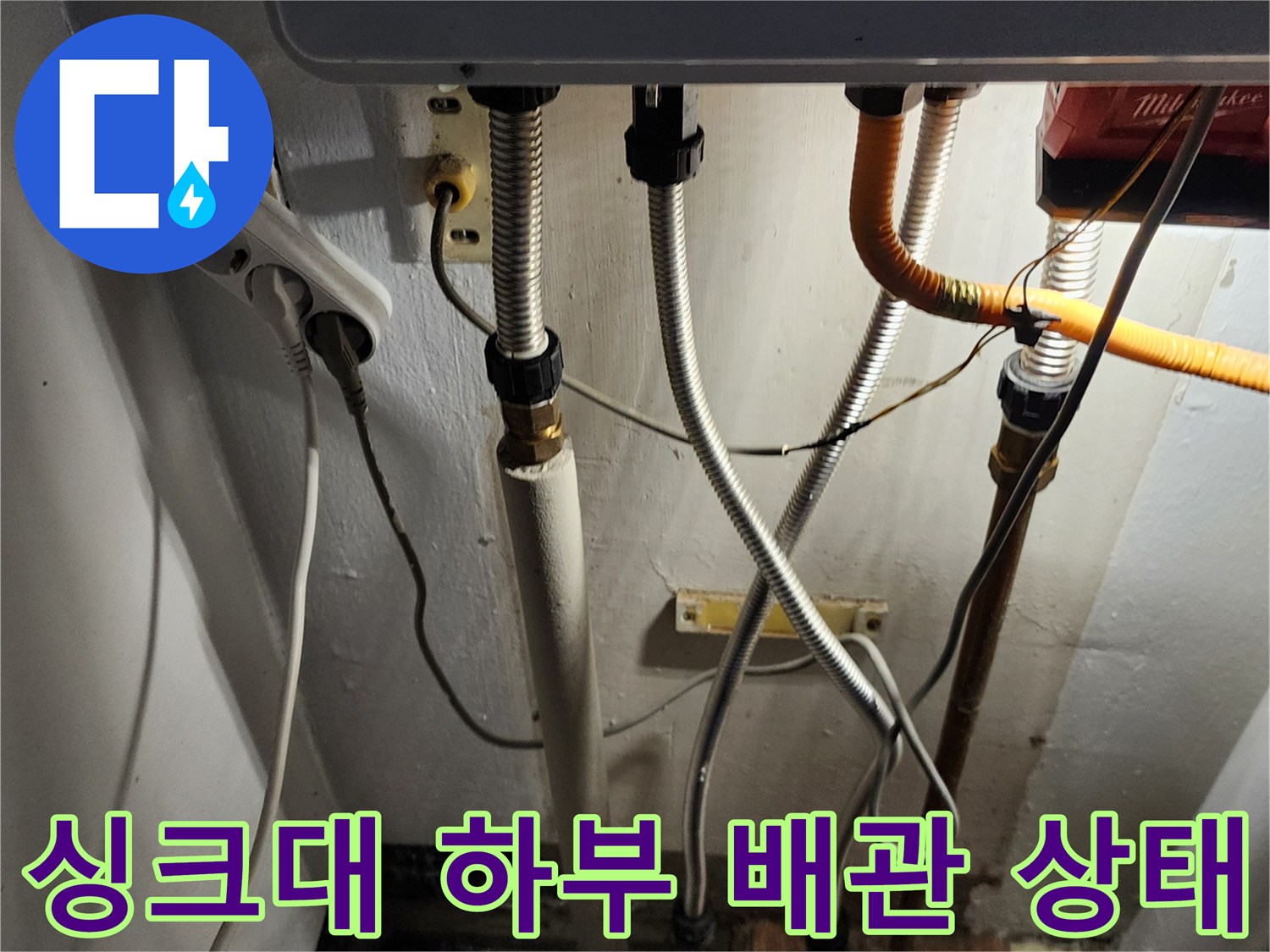 주방 싱크대 아래쪽의 복잡한 배관 연결 부위와 노후된 호스 모습