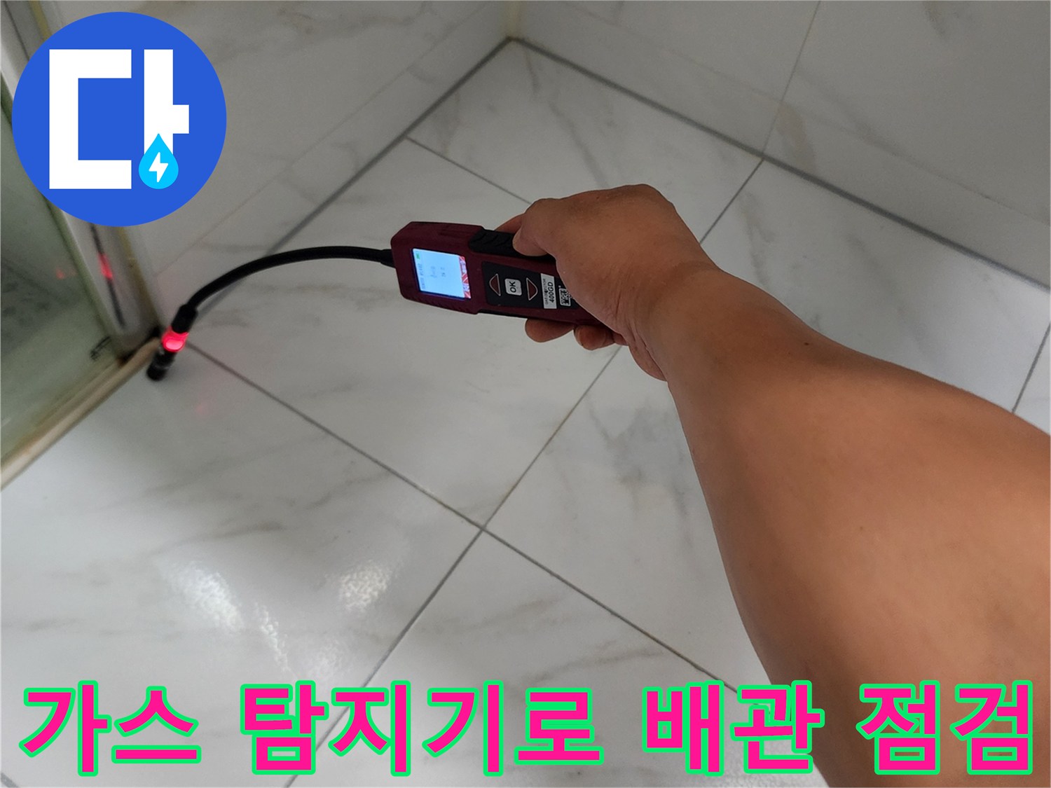 화장실 타일 벽면에 가스 탐지기를 대고 누수 지점을 찾는 모습