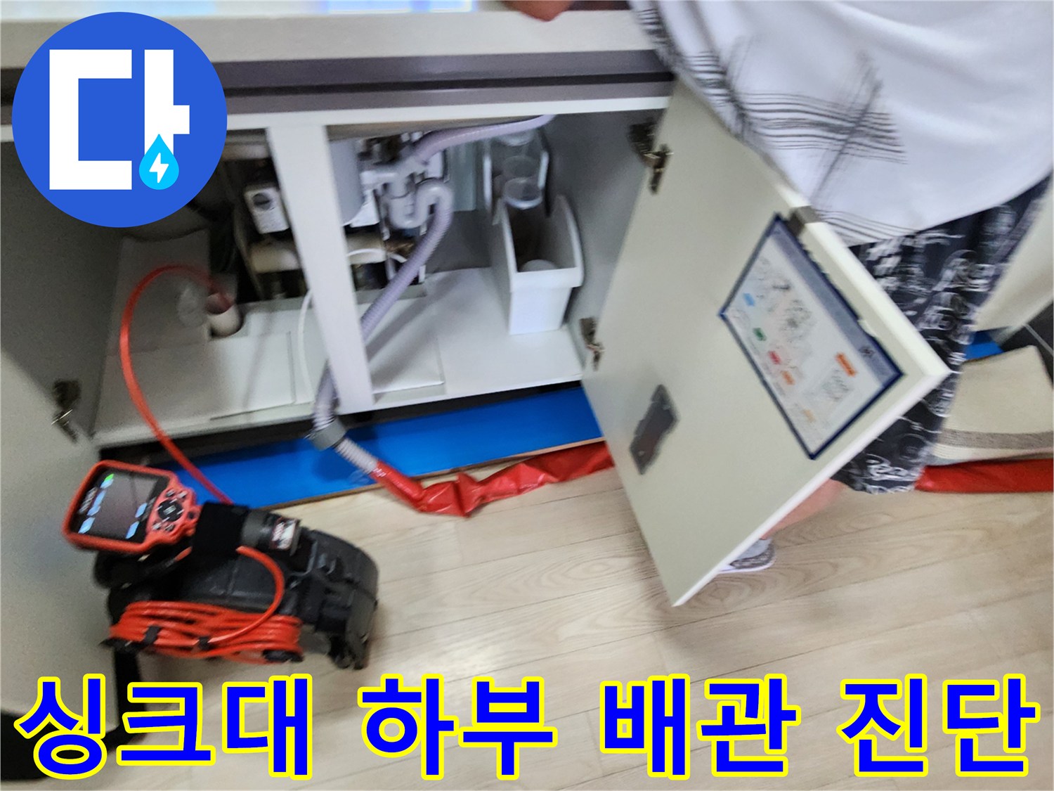 싱크대-하부장-내부의-복잡한-배관들과-측정-장비가-함께-보이는-사진