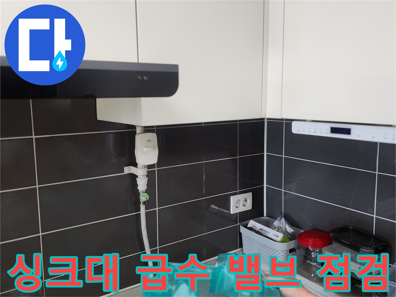 싱크대 하부장 벽면 타일에 고정된 수도 공급 밸브와 배관 호스