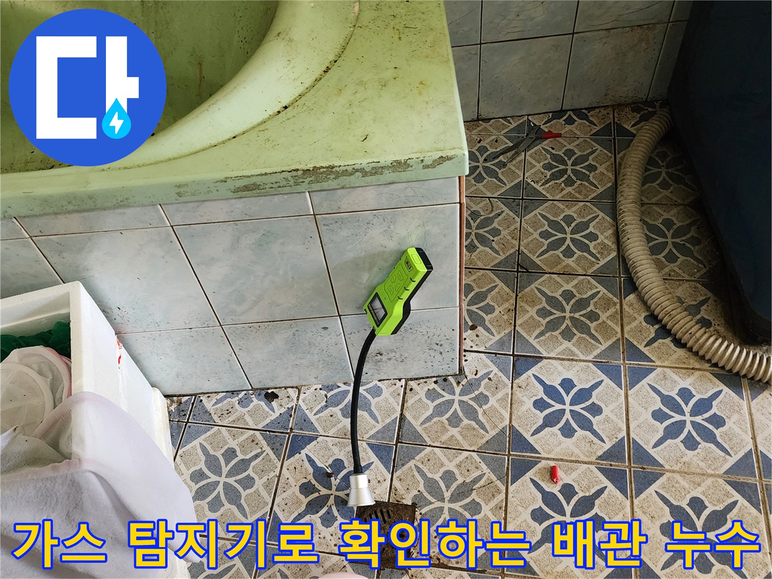 욕실 타일 바닥에 놓인 가스 탐지기와 작업용 도구들