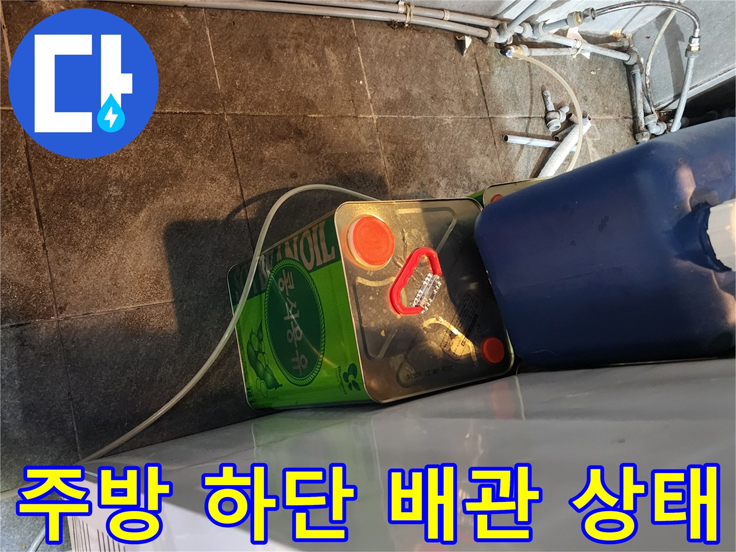 음식점 주방 하단에 위치한 복잡한 배관과 부속 연결 부위 모습