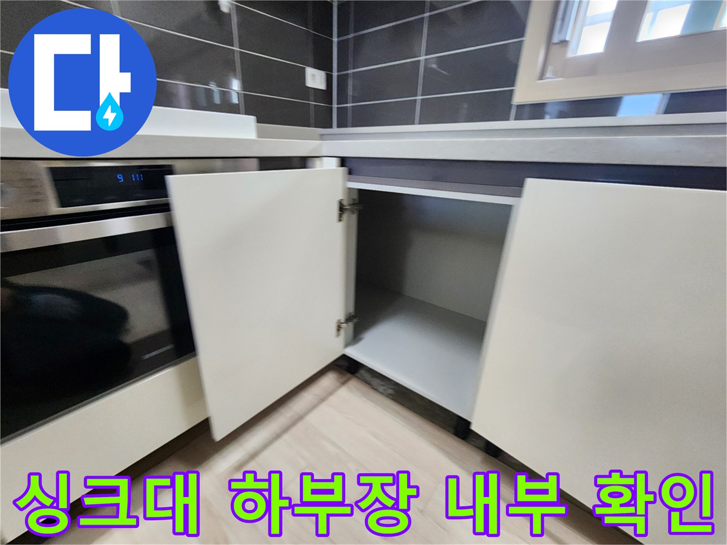 싱크대 하단 수납장을 열어 배관 주변을 관찰하는 사진