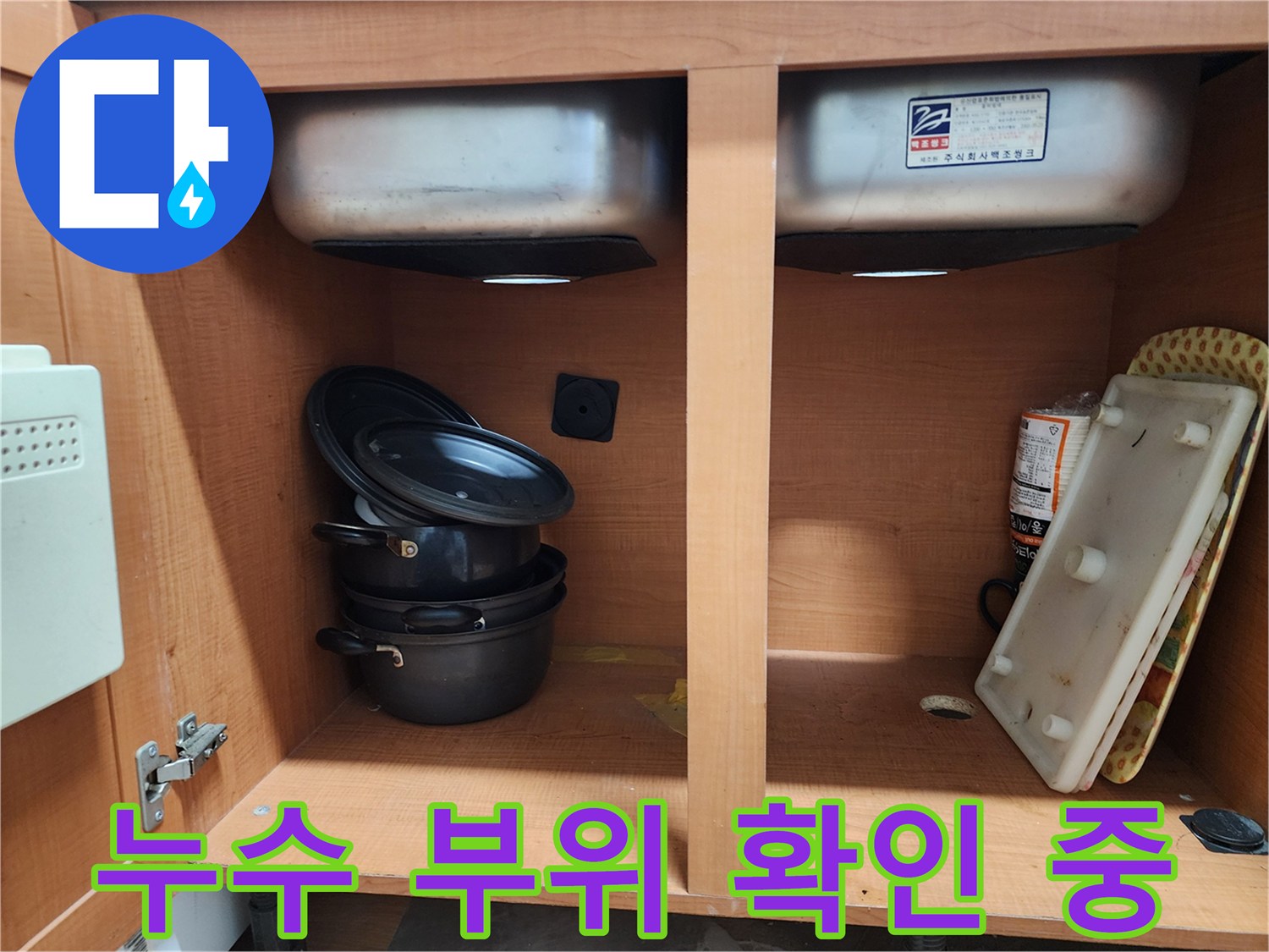 싱크대 하부장 내부 - 누수 지점을 찾기 위해 집중하고 있습니다.