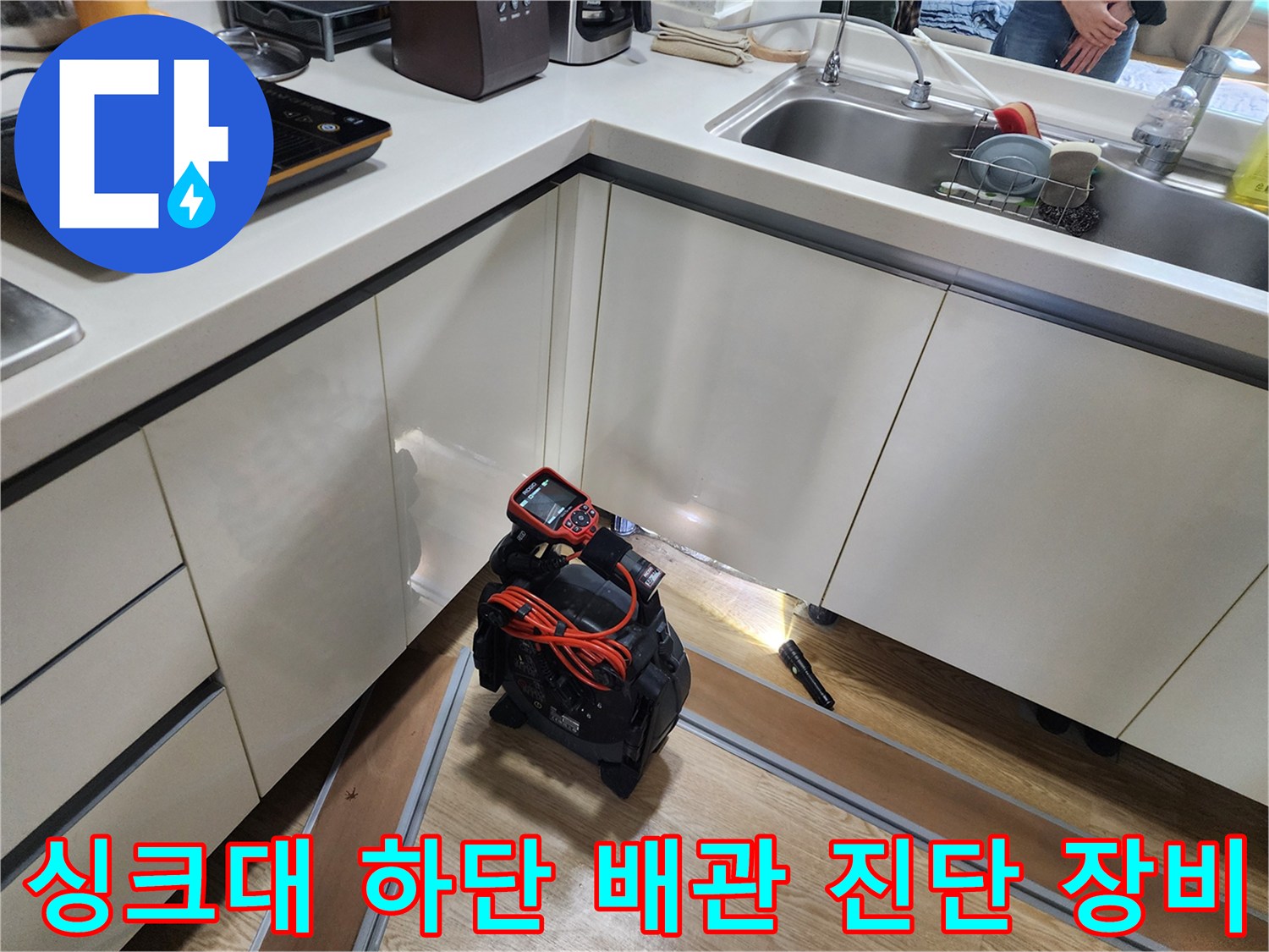 싱크대 아래 좁은 공간에 배치된 누수 탐지용 내시경 카메라와 전원선