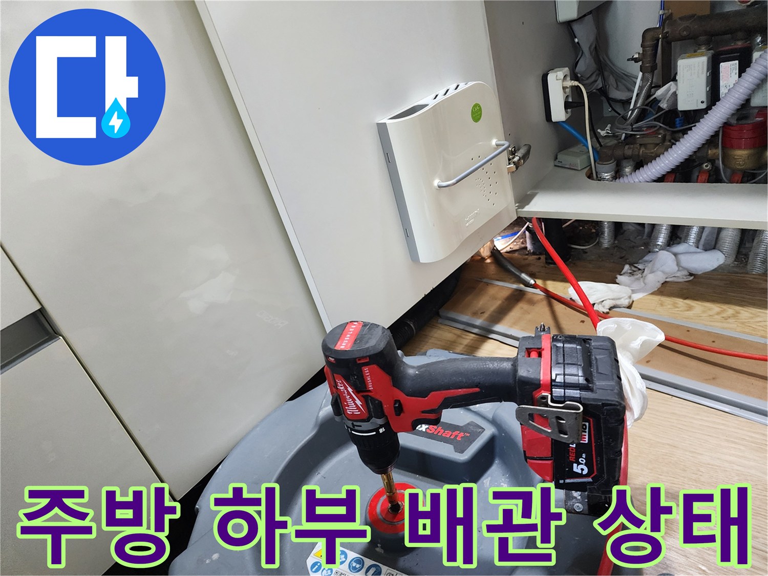 싱크대 아래쪽 복잡한 배관 구조를 점검하고 있는 작업 현장입니다.