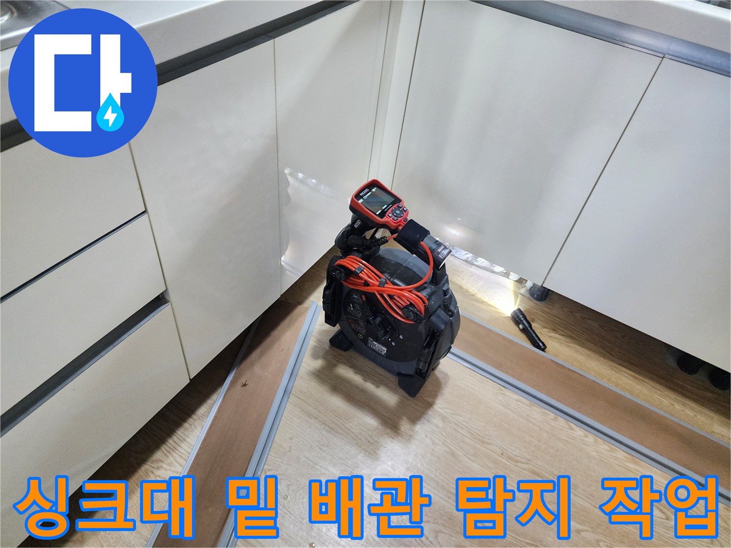 싱크대 아래쪽 어두운 공간을 비추며 배관 상태를 점검하는 내시경 장비 세팅