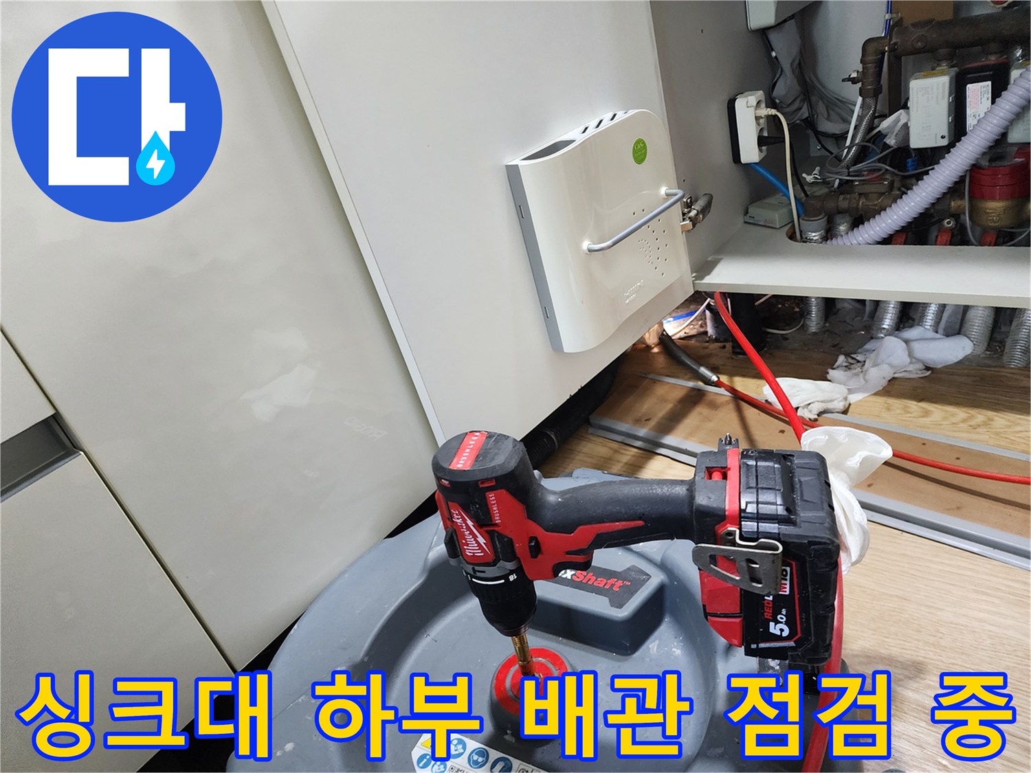 작업용 전동 드릴과 함께 배치된 싱크대 아래 배관 모습