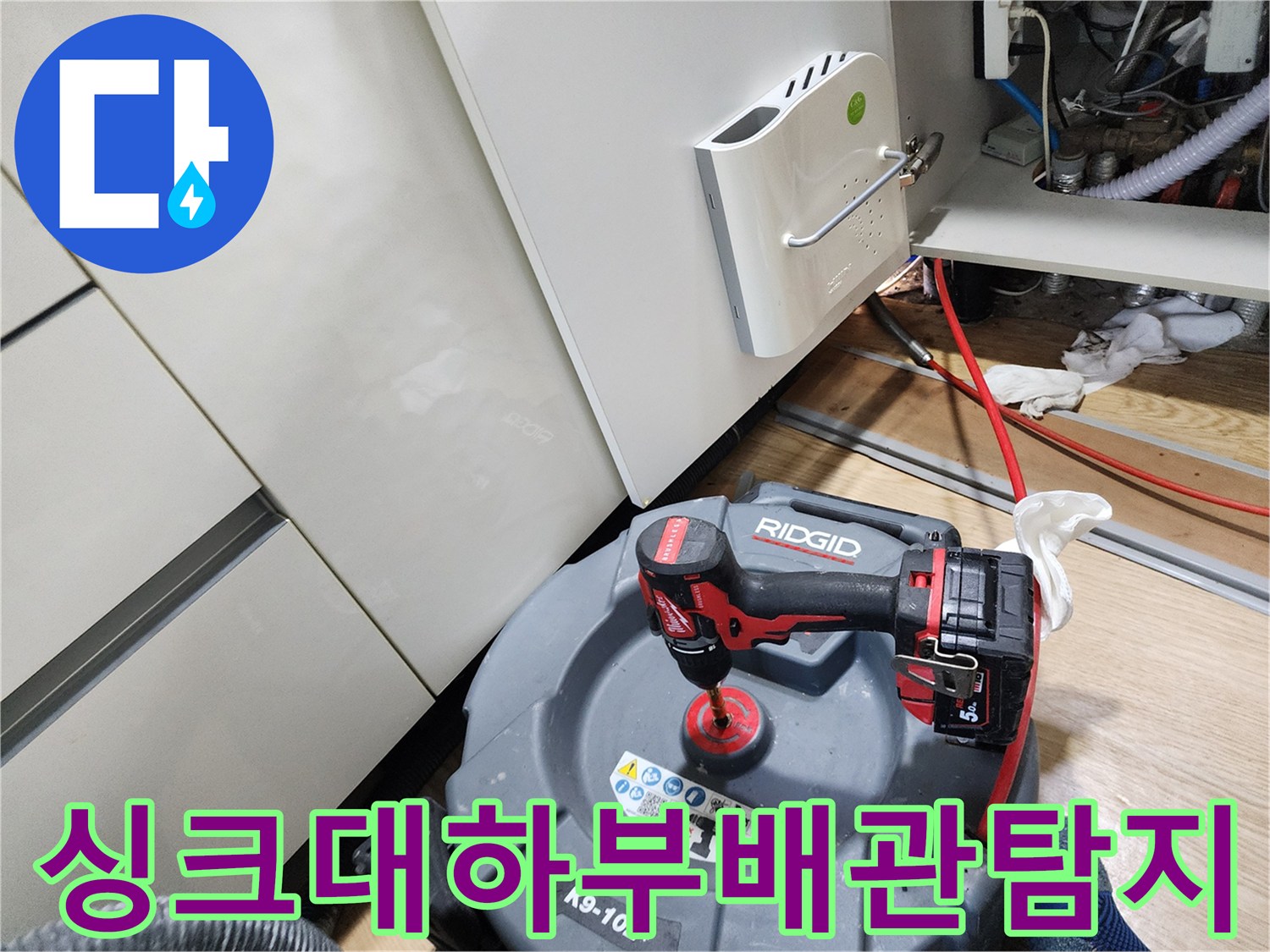 주방 싱크대 아래쪽 공간에서 배관을 점검하고 있는 모습입니다.