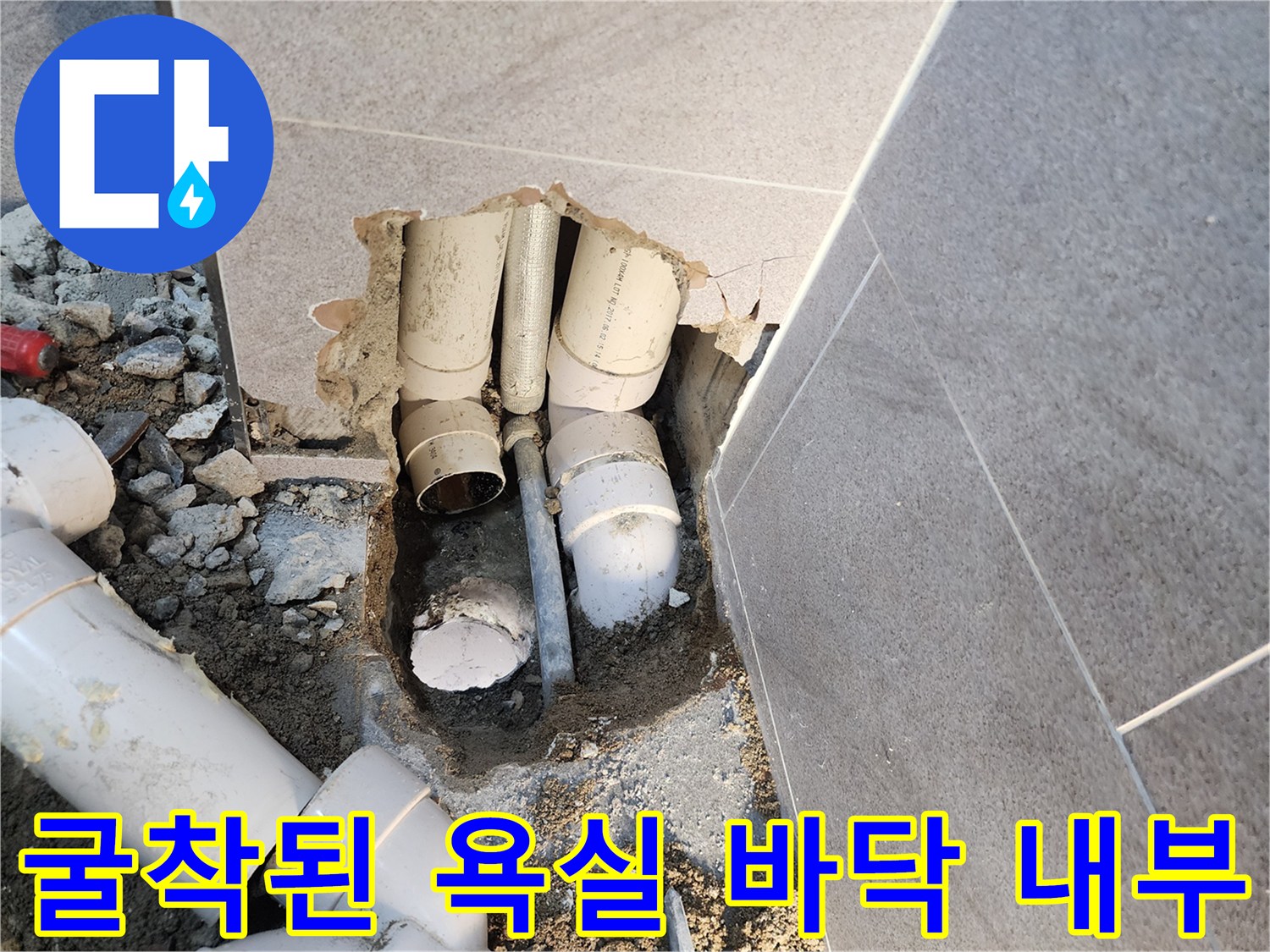 타일 제거 후 드러난 젖은 흙과 하수 배관 연결 부위