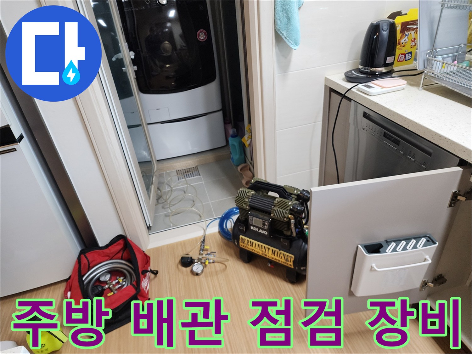 주방 싱크대 하부장 근처에 설치된 에어 컴프레셔와 작업 도구들