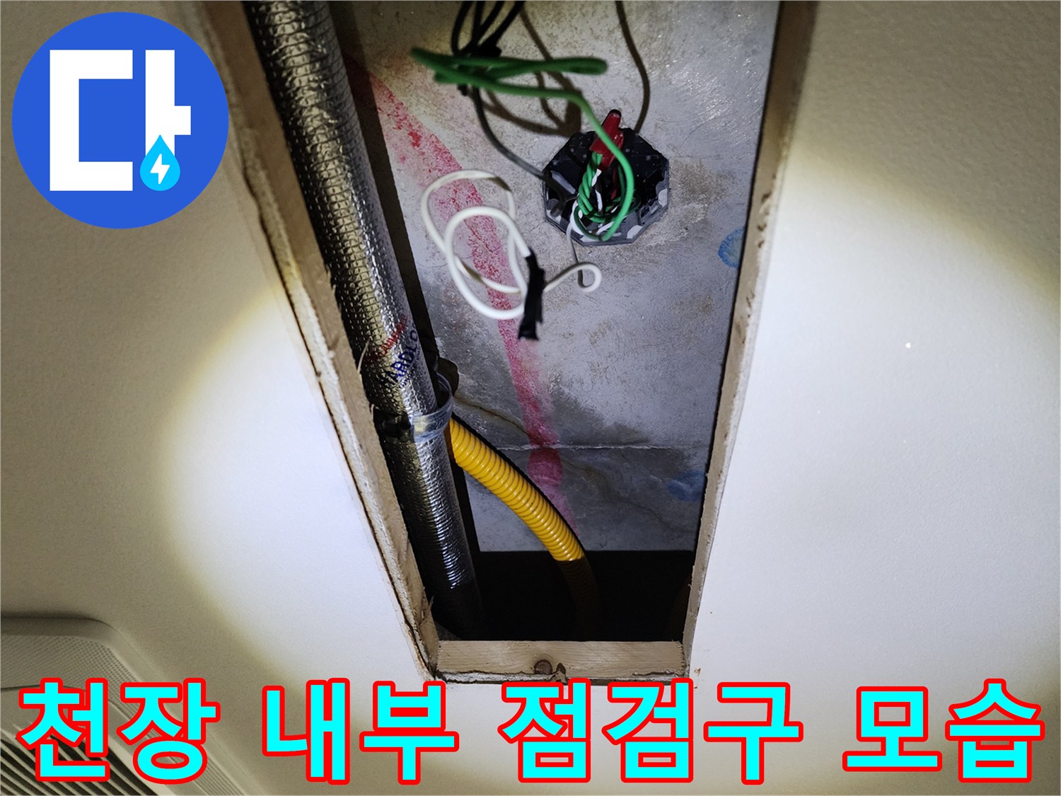 천장 점검구 내부에 보이는 금속 배관과 전선들
