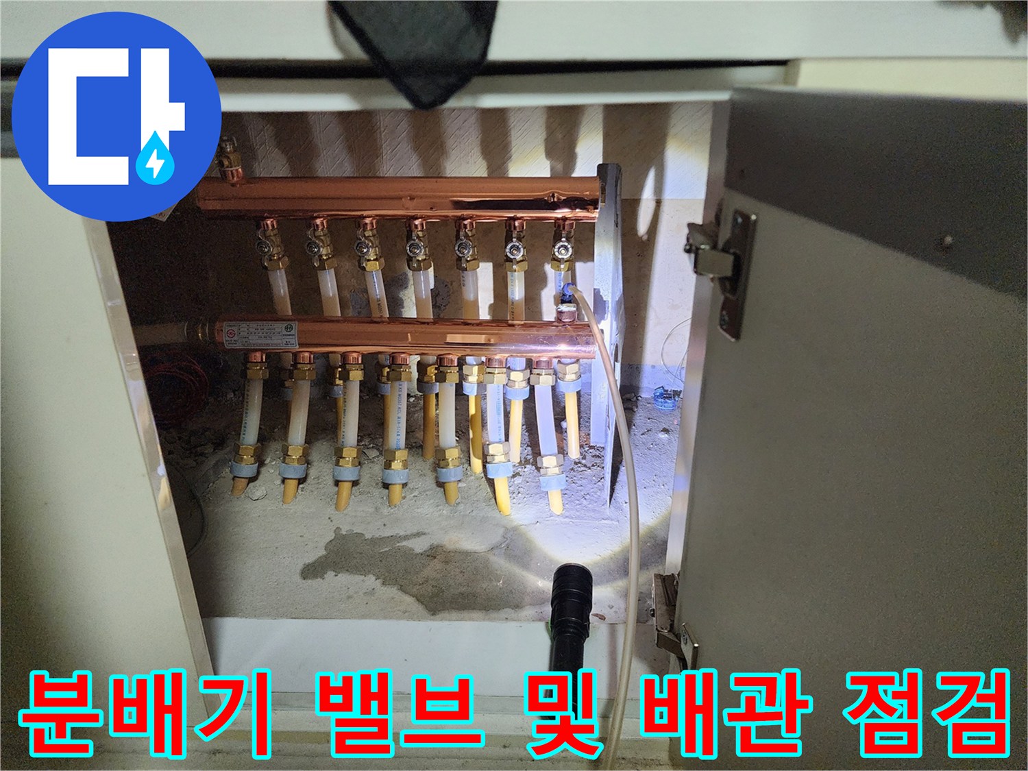 싱크대 밑 분배기에 연결된 노란색 밸브와 금속 관 부품들