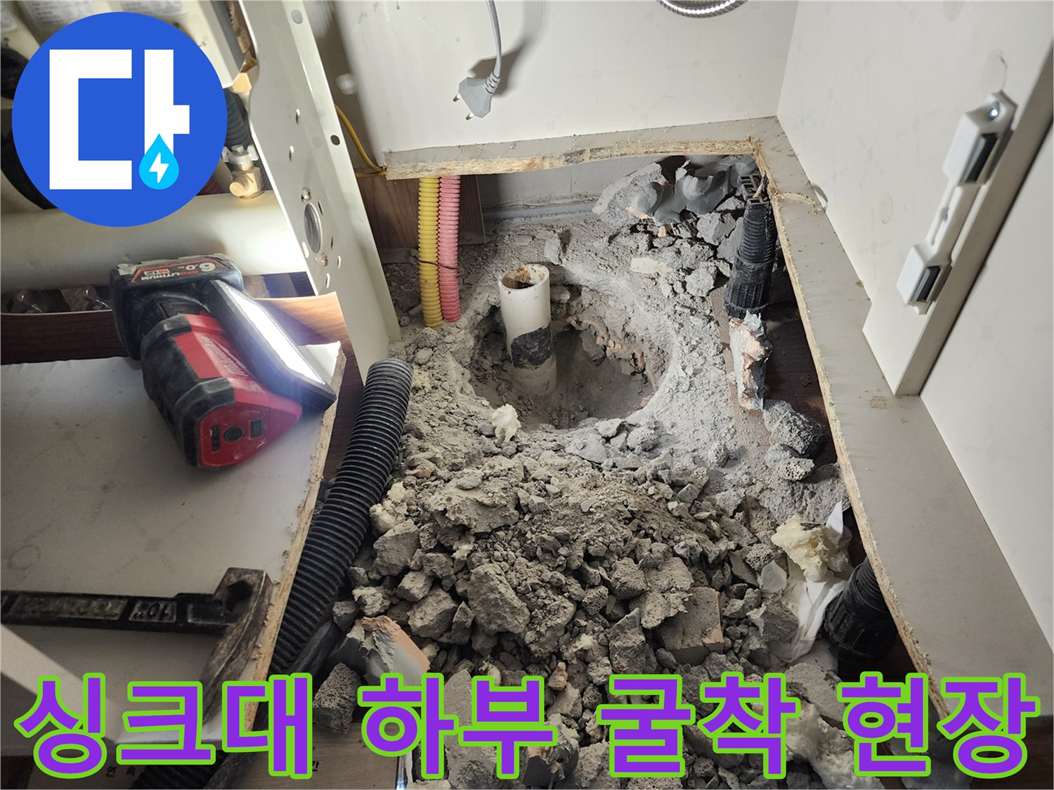 싱크대 아래 바닥을 파내어 노출된 배관과 주변의 공사 잔해물