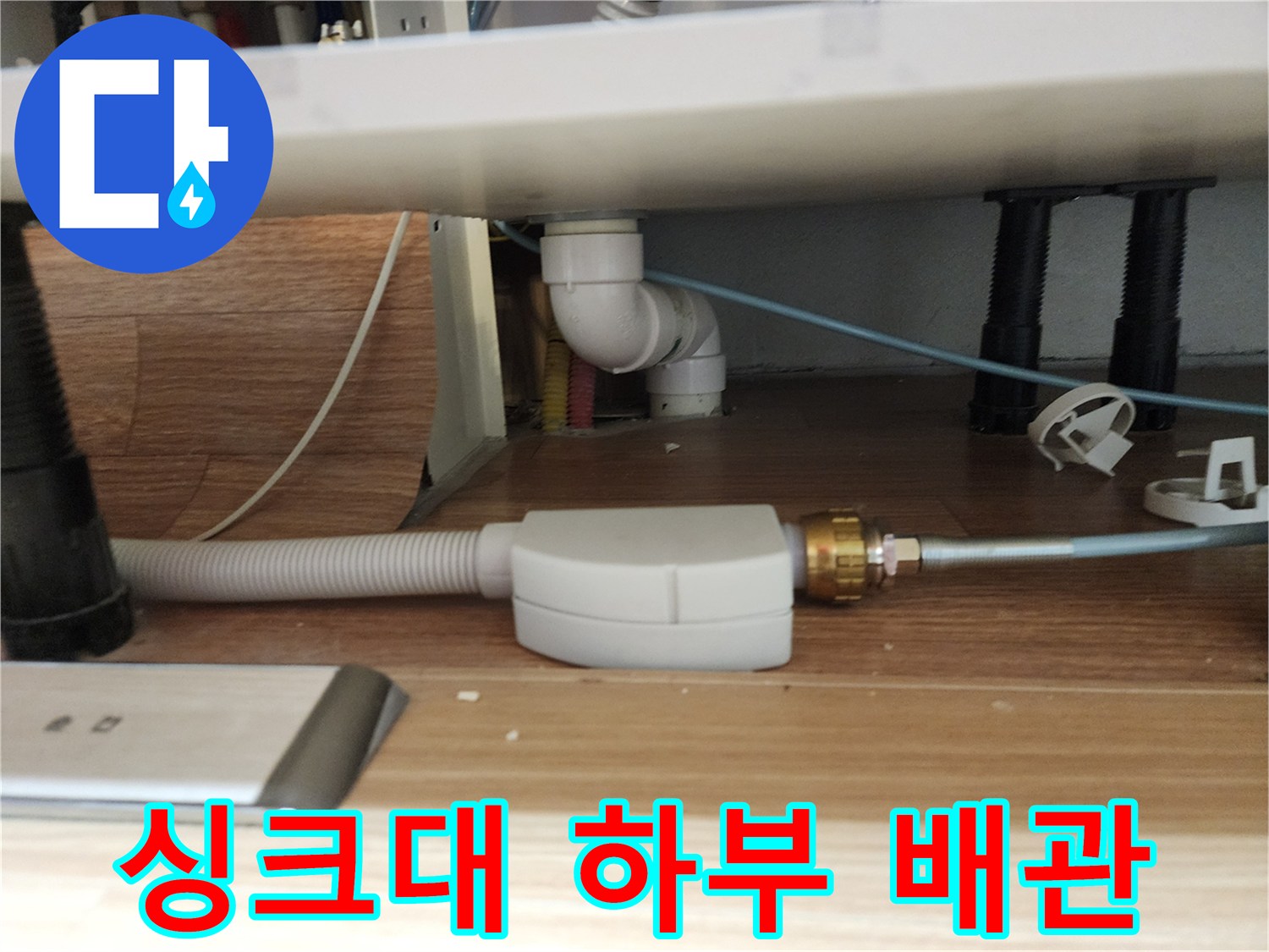 주방 싱크대 아래쪽 설치된 흰색 배수 호스와 연결 부위 모습