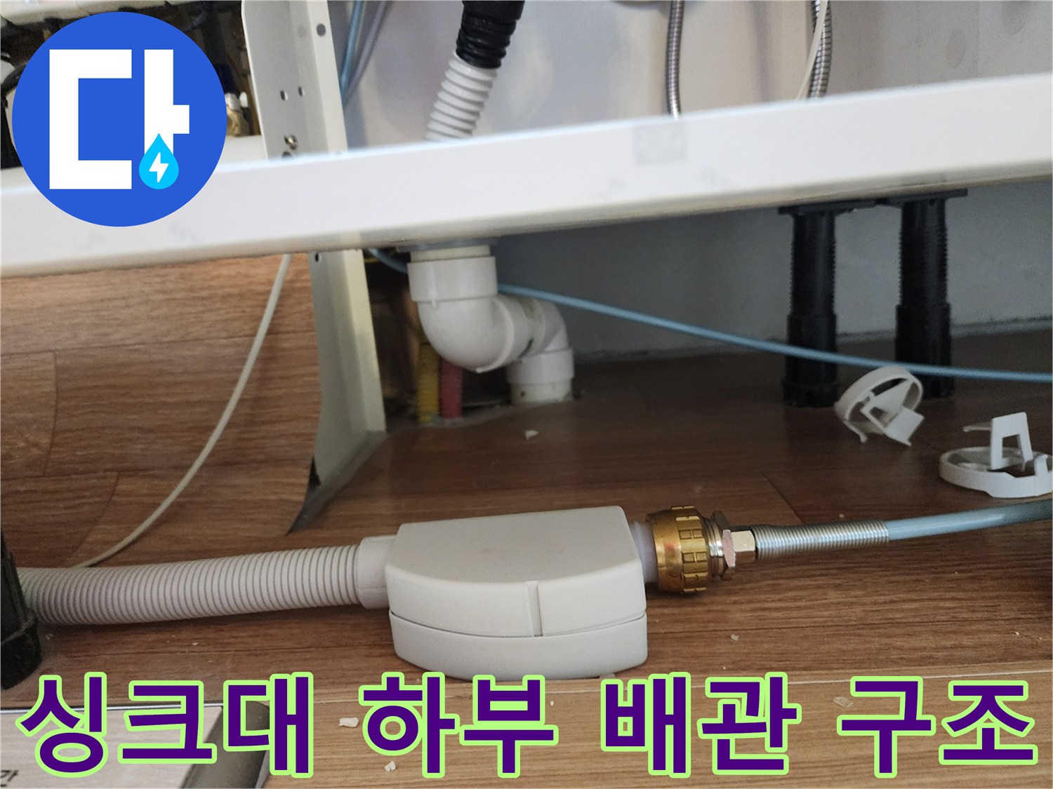 주방 싱크대 하부의 배수 호스와 연결된 금속 소재의 배관 부품 사진