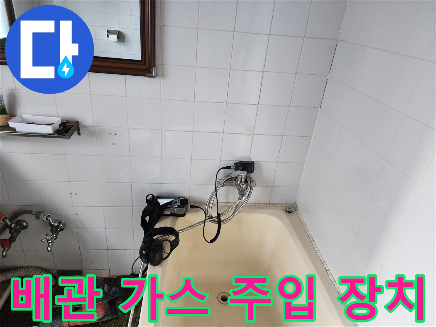 욕조 옆 타일 벽면에 연결된 배관 탐지용 호스와 압력 측정기입니다.