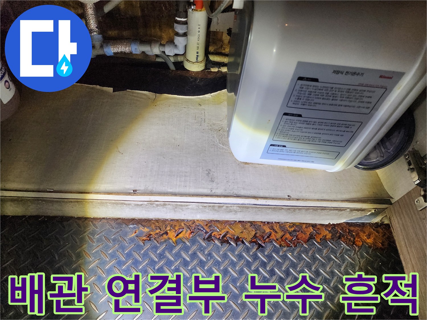 온수기 하단 배관 주변에 발생한 습기와 부식 상태를 나타냅니다.