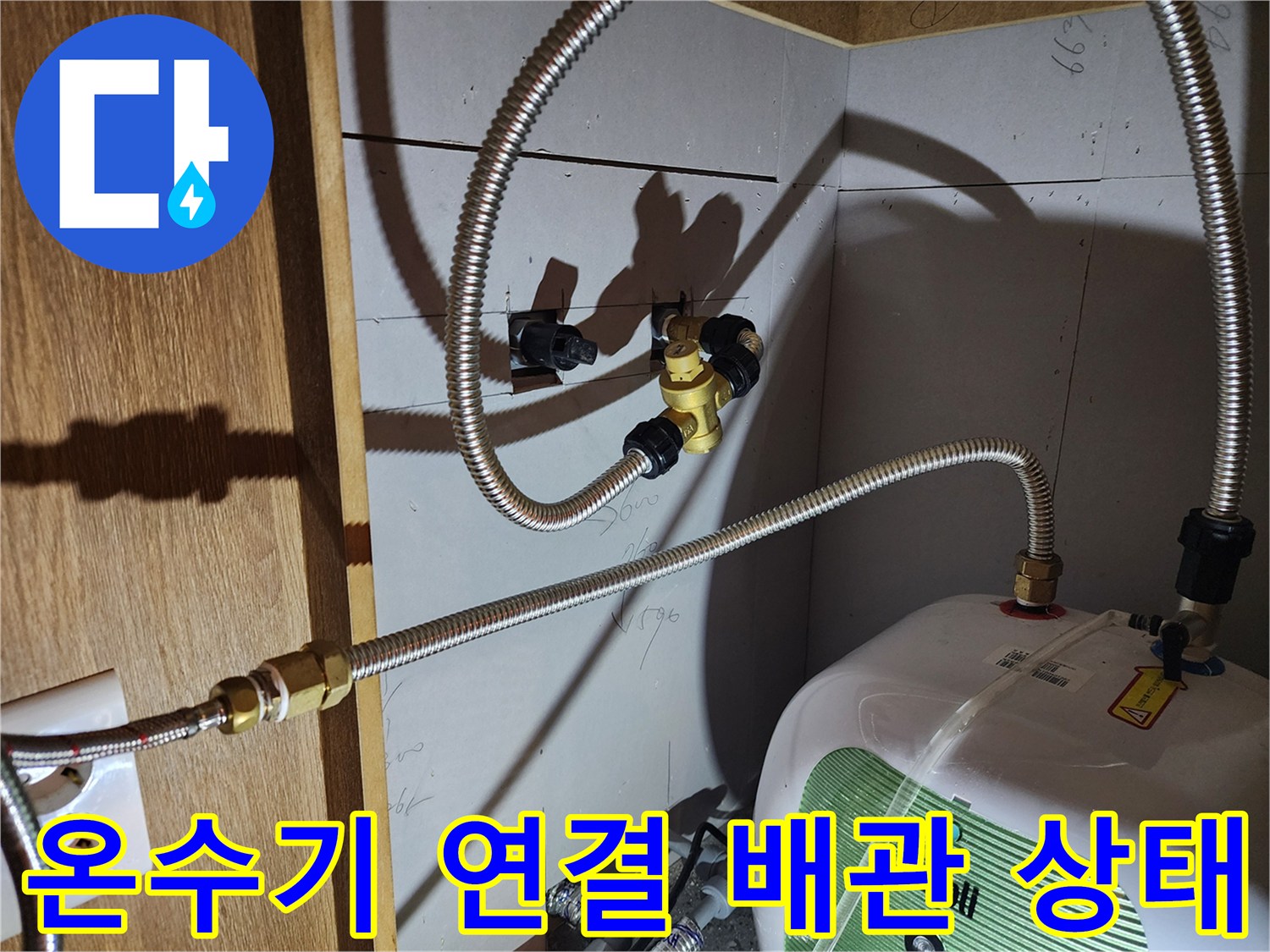 주방 싱크대 하단 - 전기 온수기와 연결된 금속 호스 부위 점검