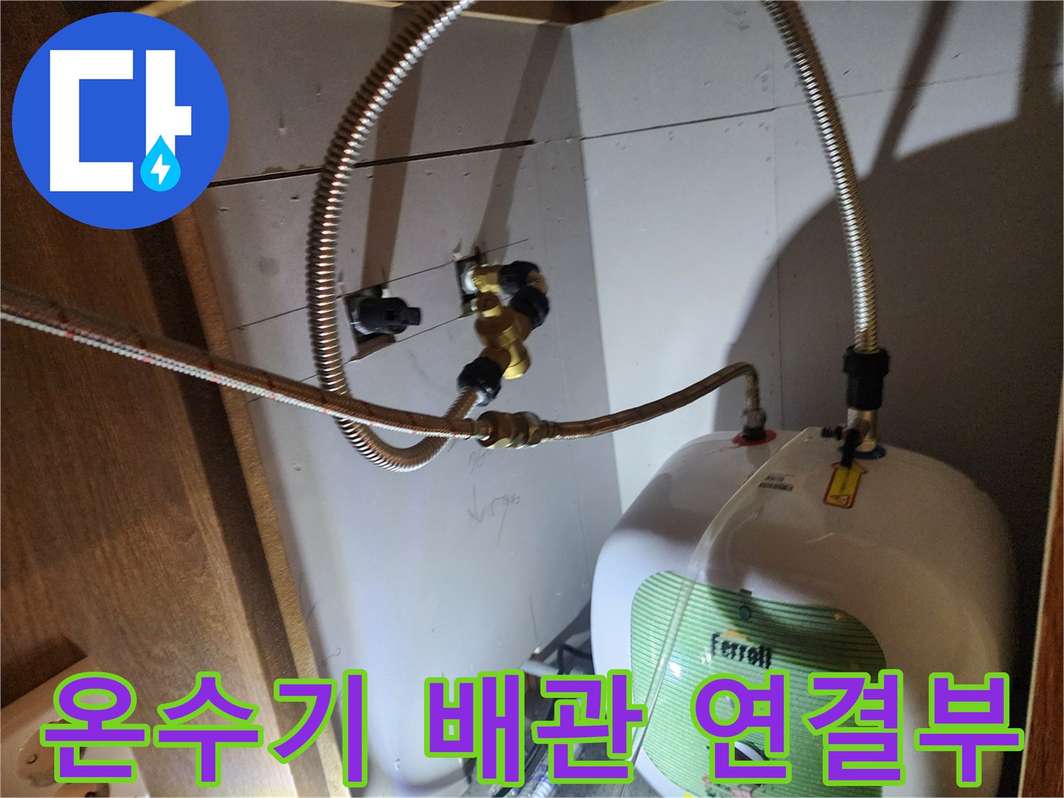 주방 하부장 내 설치된 전기 온수기와 금속 플렉시able 호스 연결 부위 모습