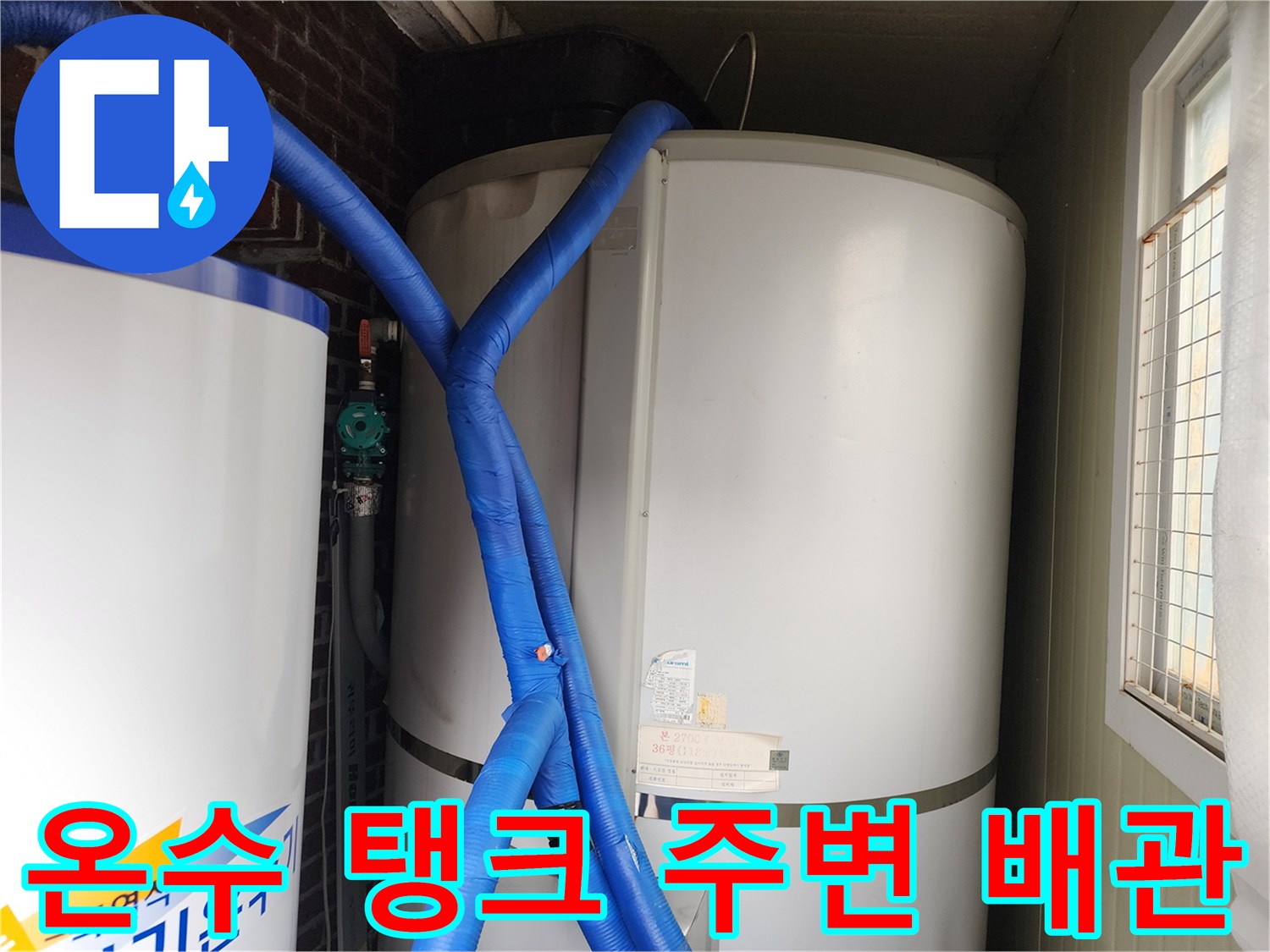 파란색 보온재가 적용된 배관이 대형 온수 탱크에 연결되어 있는 사진입니다.