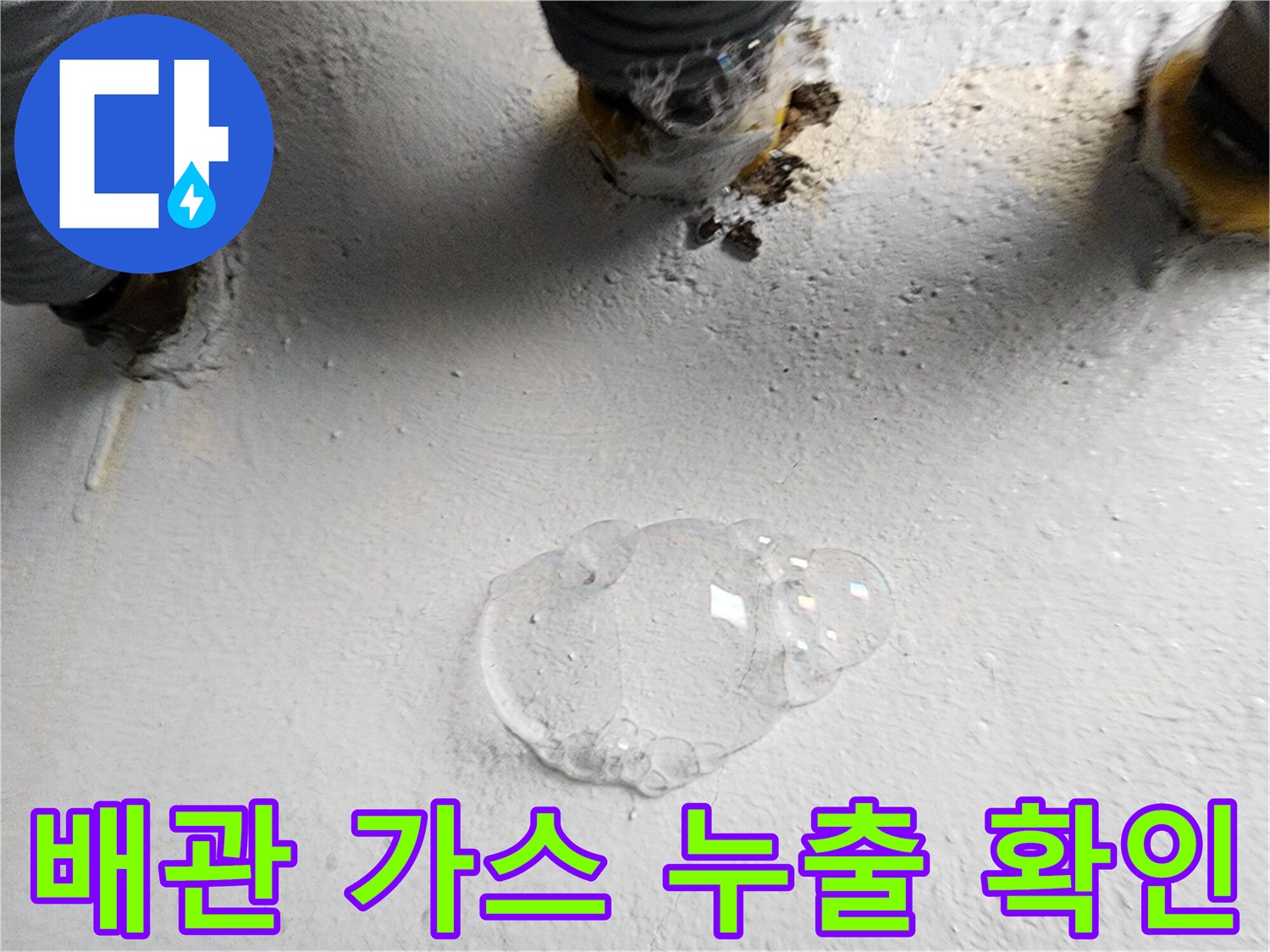 바닥 배관 연결 지점에 거품이 생기며 공기가 새어 나오는 상태를 보여줍니다.