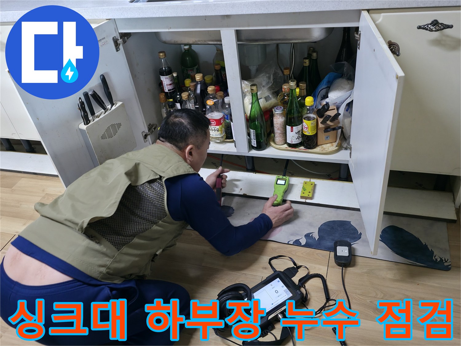 주방 싱크대 하부장 내부에서 가스 탐지기를 사용하여 배관 상태를 확인하는 모습입니다.