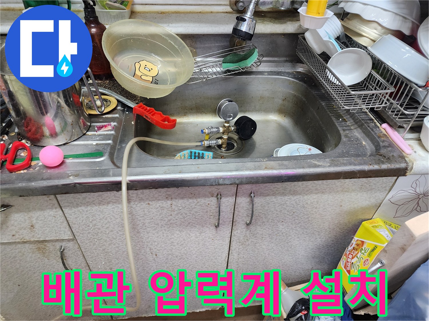 싱크대 하부 배관에 연결된 공압 테스트 장비와 게이지