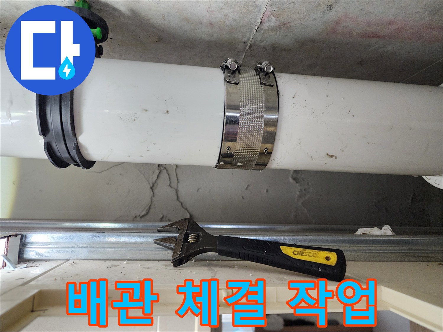 금속 클램프로 단단하게 조여진 배관과 작업용 렌치 도구