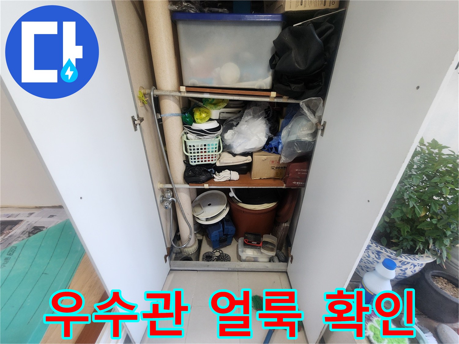 베란다 수납장 안에 우수관이 있습니다-다양한 물건들이 정리되어 있지 않은 상태입니다-누수 탐지를 위한 현장 사진입니다