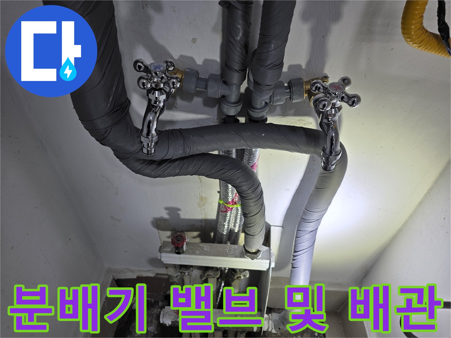 보온재로 마감된 배관과 금속 재질의 분배기 밸브 모습