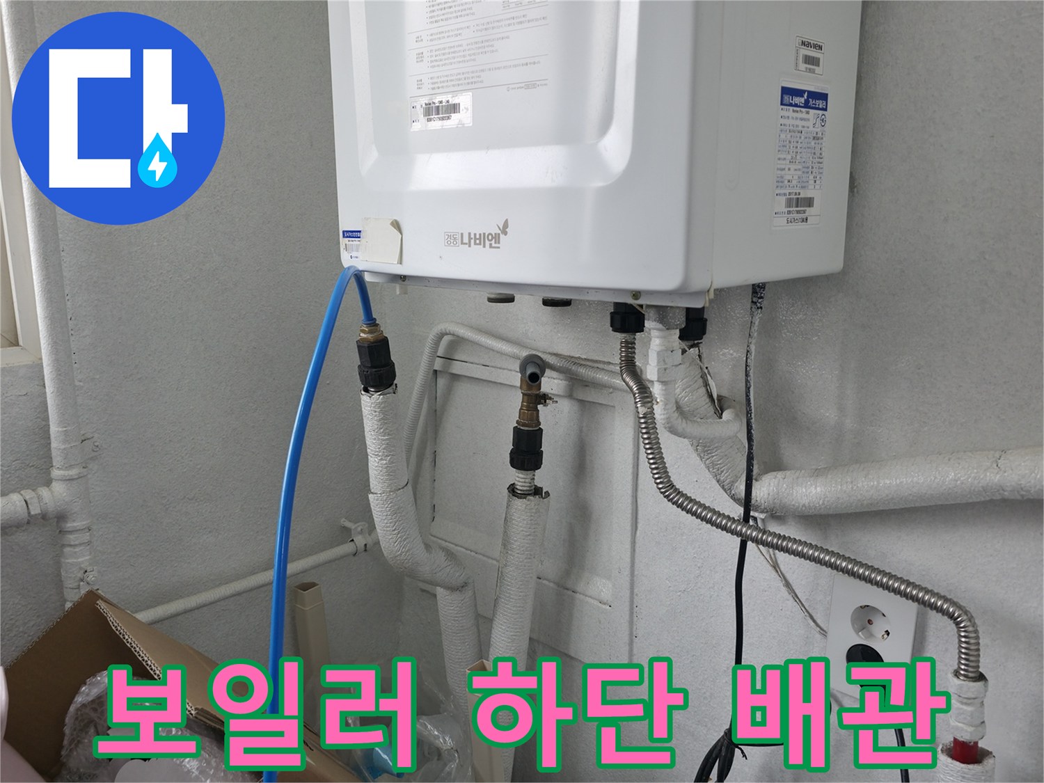 보일러 본체 아래로 연결된 수도 배관과 호스들의 상세 사진입니다.