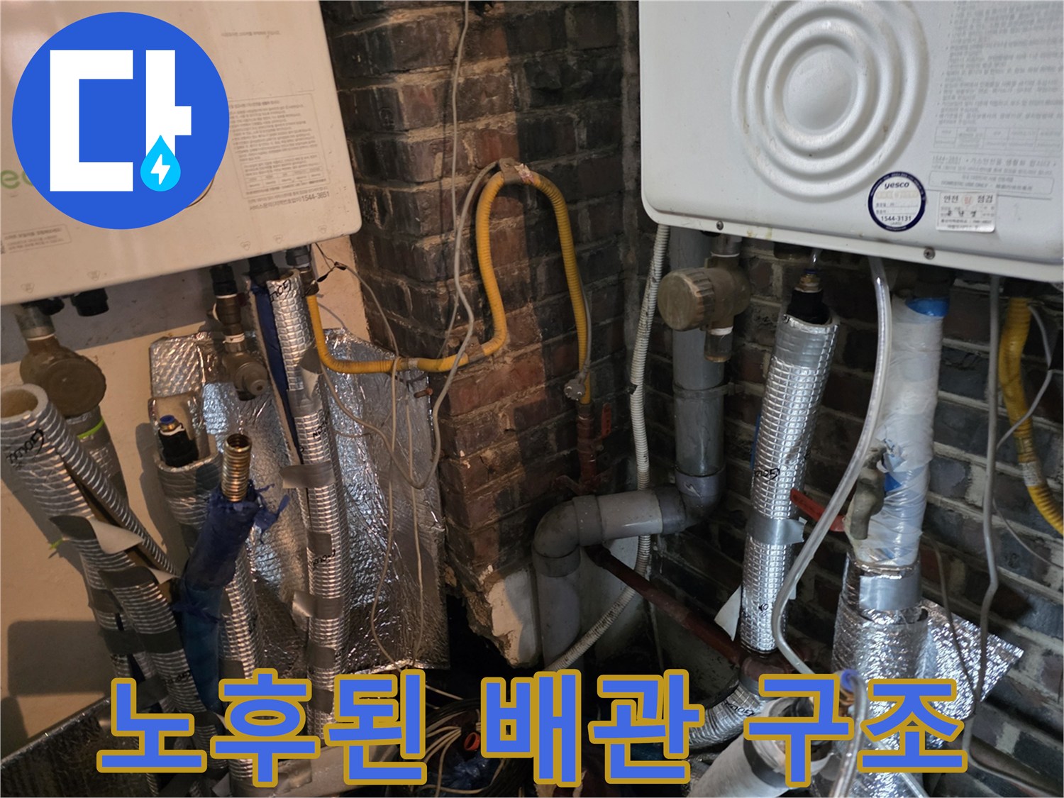 벽돌 벽면을 배경으로 설치된 보일러와 하부의 다중 배관 연결부