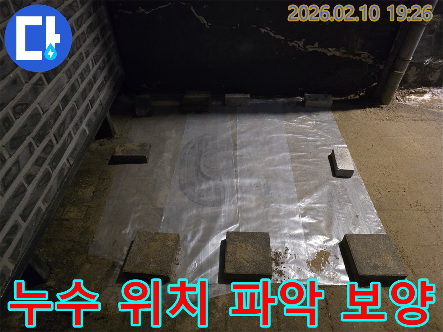누수-공사-현장에서-바닥에-투명한-보호-비닐을-깔고-무거운-자재로-고정하여-작업-준비를-하는-모습입니다.