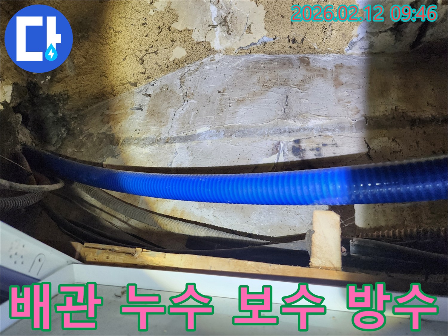 식당 내부의 낡은 벽면과 파란색 배관-주변의 누수 지점을 보수하고-방수 처리하는 전문가의 작업 모습입니다.