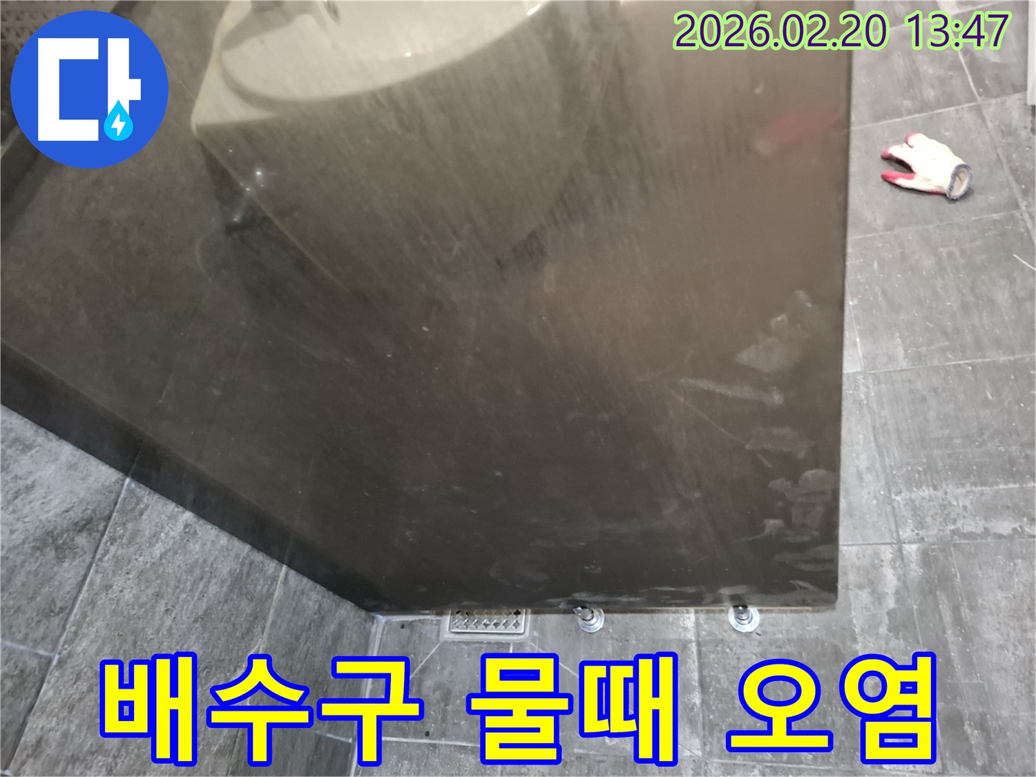 욕실 배수구 주변 바닥 타일에 나타난-지속적인 물 접촉으로 인한 물때와-오염 현상을 보여주는 사진