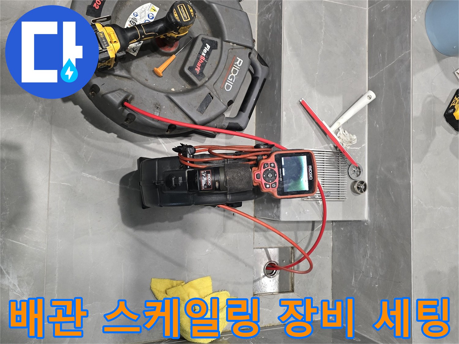 욕실 타일 위에서 가동 대기 중인 배관 내시경 카메라와 청소용 장비