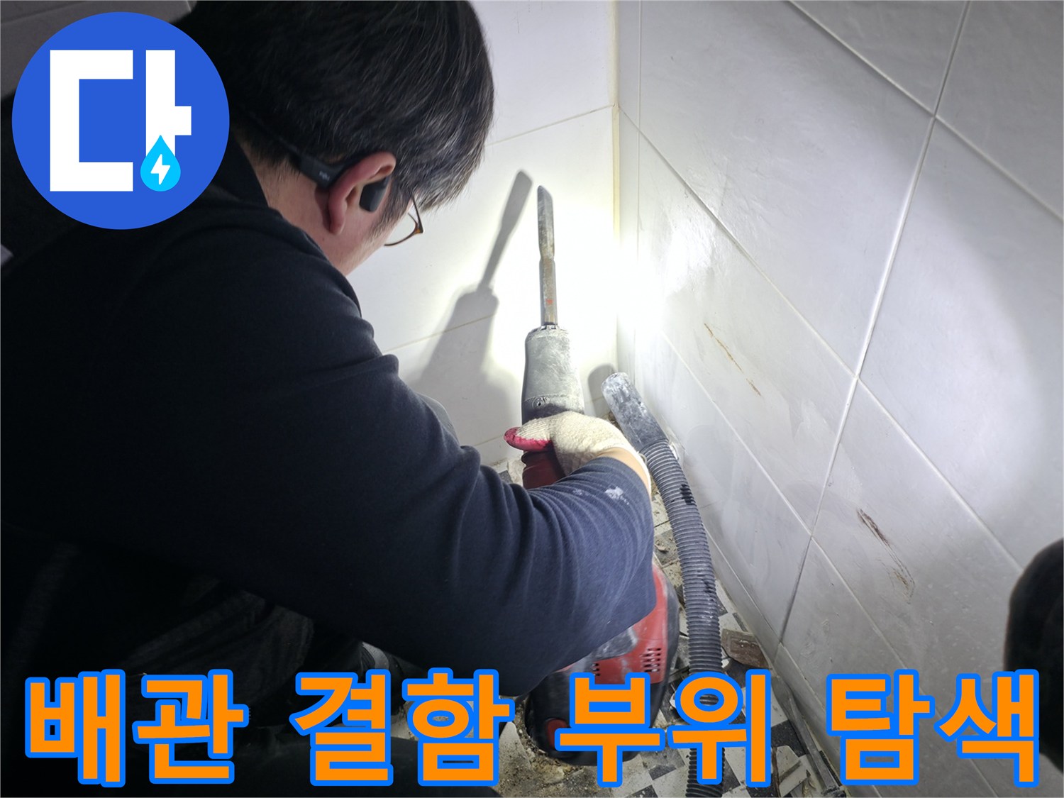 어두운 타일 틈새를 조명으로 비추며 누수 지점을 찾는 모습